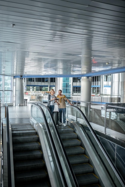 Airport passengers scrutinizing travel documents on the escalator