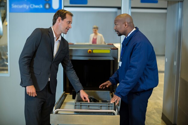 Airport security officer interacting with commuter while checking a package