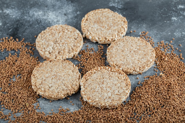 Airy crispbread and raw buckwheat on marble surface