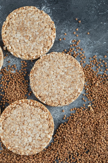 Airy crispbread and raw buckwheat on marble surface