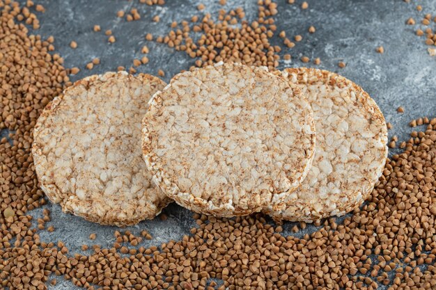 Airy crispbread and raw buckwheat on marble surface