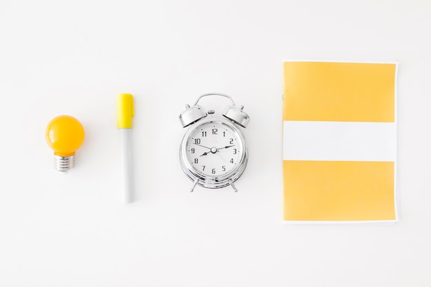 Alarm clock and bulb near stationery