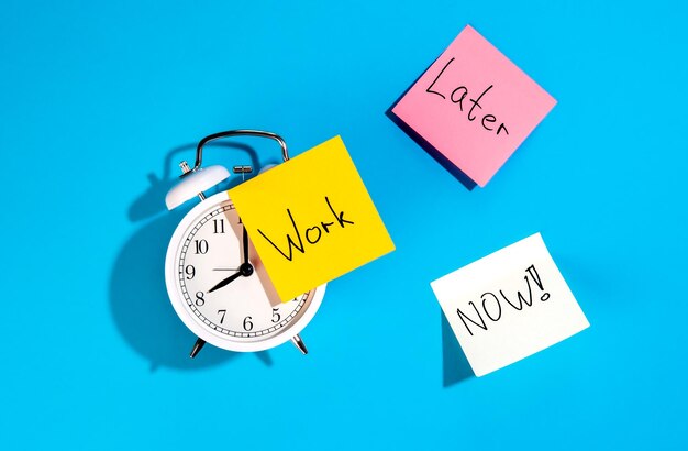 Alarm clock and colorful paper reminders on a blue background top view