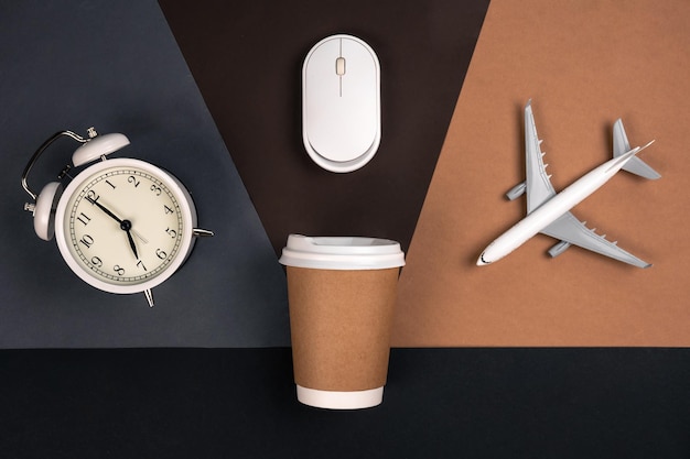 Alarm clock computer mouse cup and airplane on a paper background top view