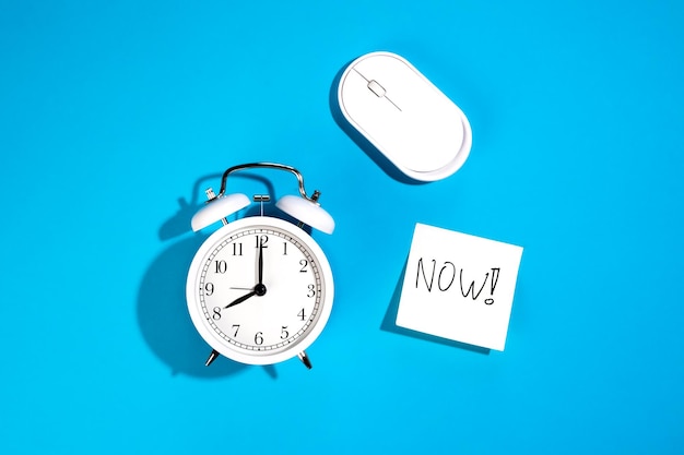 Free photo alarm clock computer mouse and a paper with inscription now