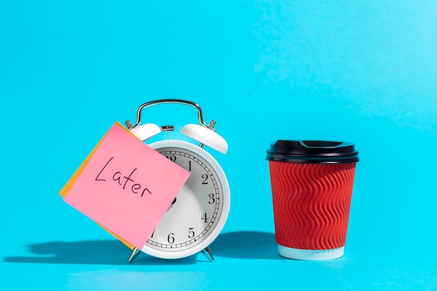 Free photo alarm clock cup and a sticker with the inscription late on a blue background