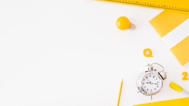 Alarm clock and light bulb near assorted stationery