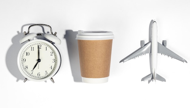 Free photo alarm clock paper cup and airplane model on white background