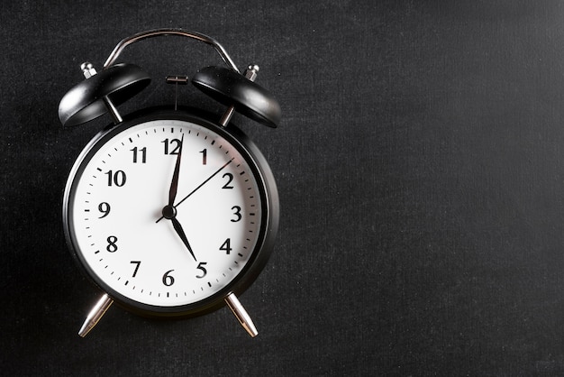 Alarm clock showing 5'o clock against black background