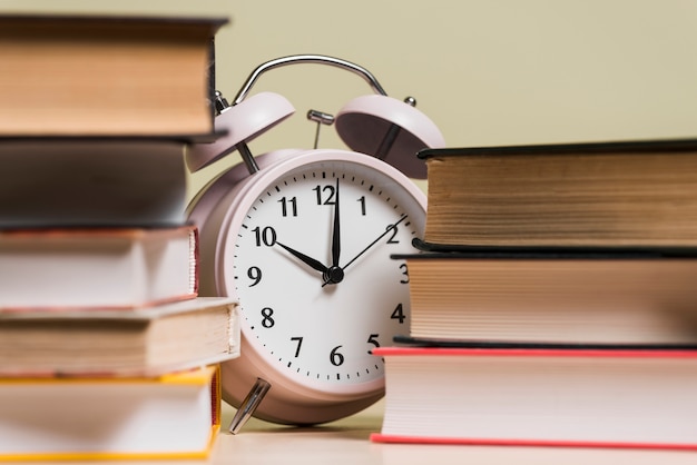 Alarm clock showing the time 10'o clock behind the bookshelf