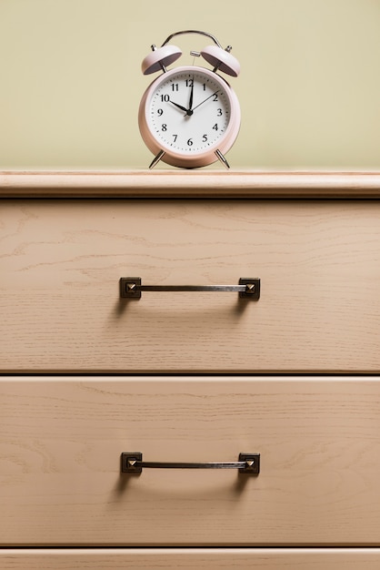 Free photo an alarm clock on top of wooden cabinet