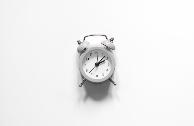 흰색 배경에 알람 시계가 평평하게 놓여 있는 흑백 사진
