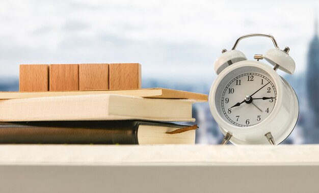 Alarm clock and wooden cubes on books on a table