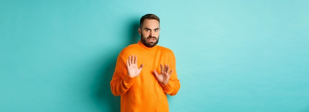 Free photo alarmed guy shaking hands in rejection declining and stepping away scared standing over light blue b