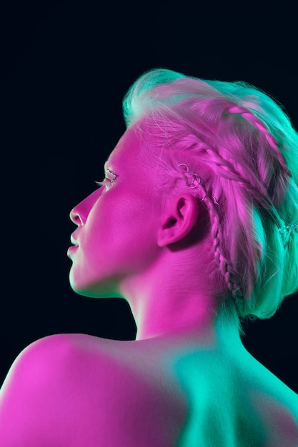 Albino girl with white skin, natural lips and white hair in neon light isolated on black studio background.