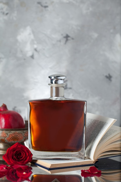 Free photo alcohol bottle on a book with pomegranates and rose