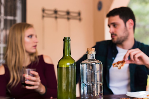 Alcohol bottle in front of couple eating food