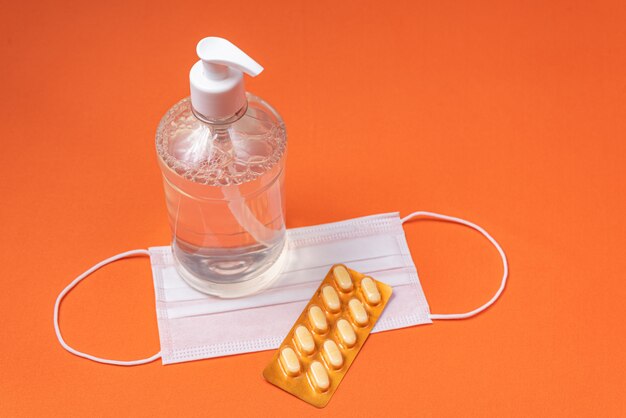 Free photo alcohol gel container, surgical mask, medicine on the orange wall