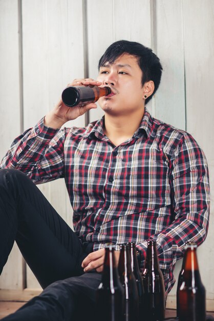 Alcoholic asian man sitting alone drinking beer