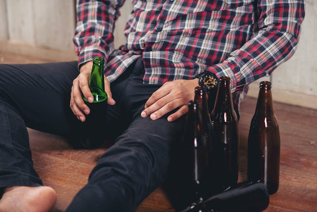 Alcoholic asian man sitting alone with beer bottles