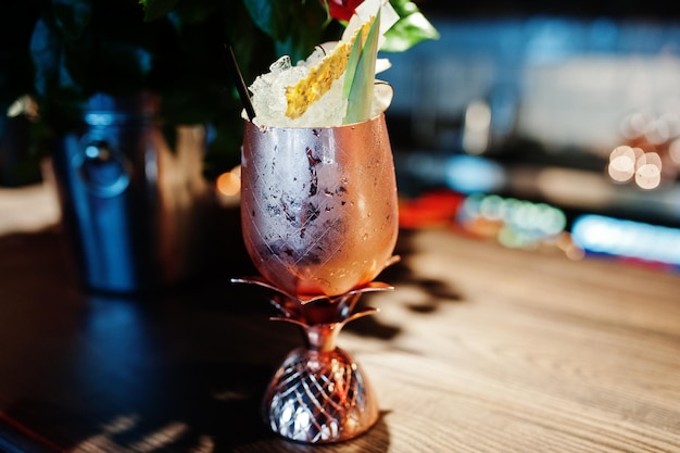 Alcoholic cocktail with ice in bronze glass on bar table