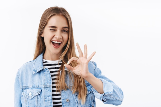 Free photo all okay relax carefree assertive young blond female coworker assure work done well give positive feedback show ok gesture and smile nod in approval praise nice job stand white background