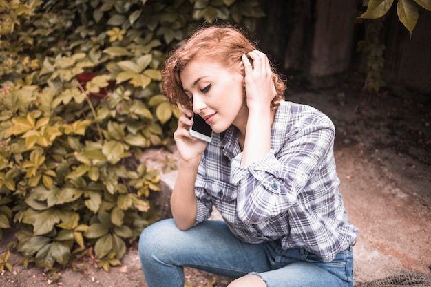 Alluring female with device at street with bushes