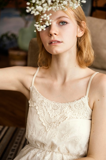 Alluring woman posing next to sofa while holding beautiful spring flowers