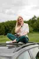 Free photo alluring woman posing on top of car