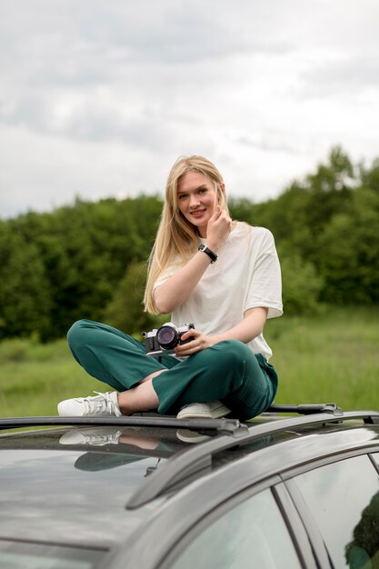 Alluring woman posing on top of car