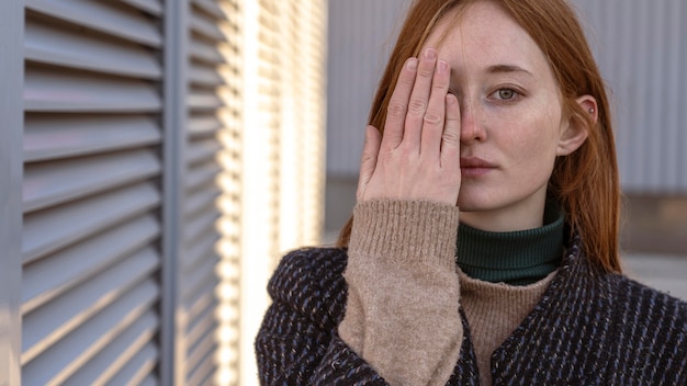 Free photo alluring woman posing while covering half her face with hand