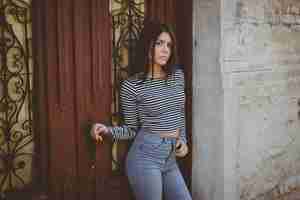 Free photo alluring young woman in casual clothing posing beside a wooden door