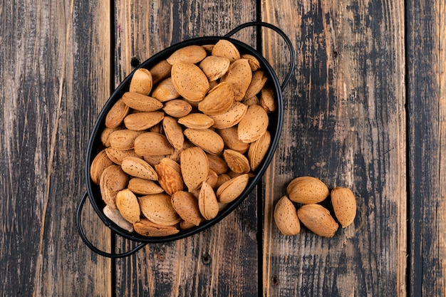 Almond in a black pan on a dark wooden table. top view.