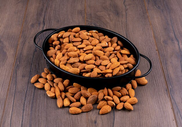 Almond in a black pan high angle view on a white wooden table