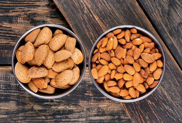 Almond in a iron bowls on a dark wooden table. top view.