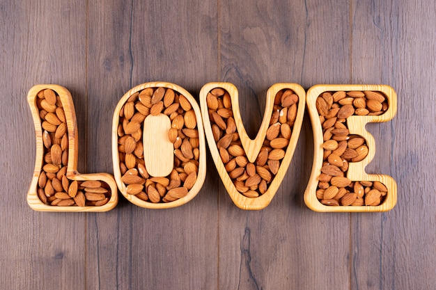 Almond in a love shaped plates flat lay on a wooden table