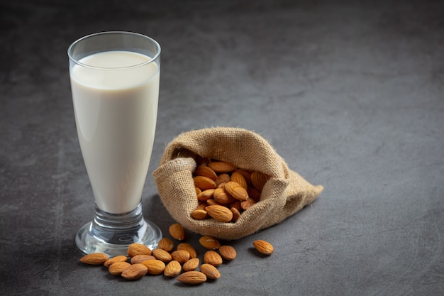 Almond milk with almond on dark background