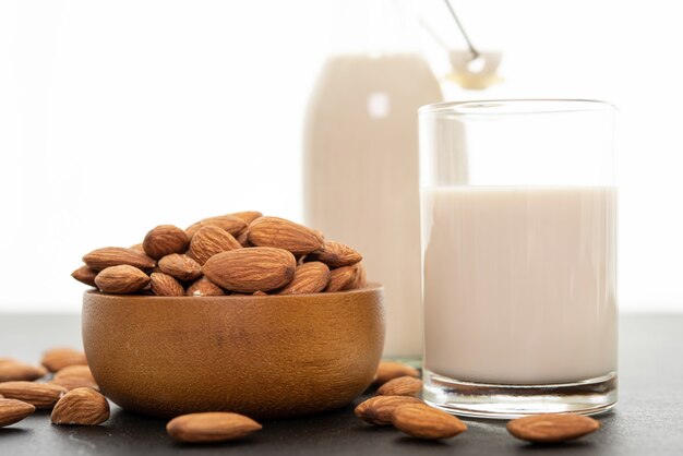 Almond milk with almond in a wooden bowl on black background.