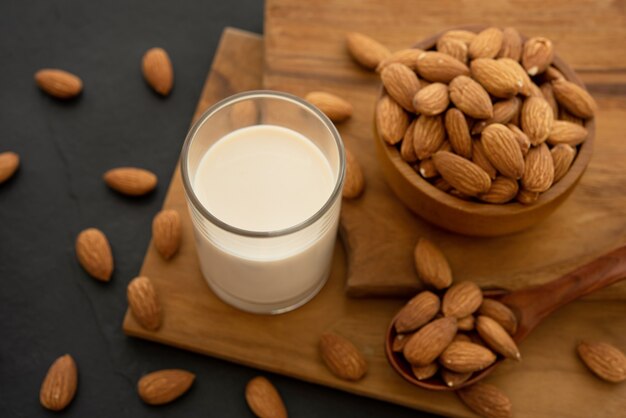 Almond milk with almond in a wooden spoon and bowl on a wooden