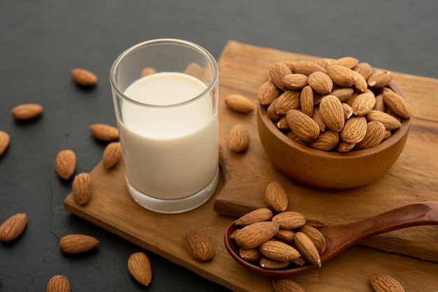 Almond milk with almond in a wooden spoon and bowl on a wooden