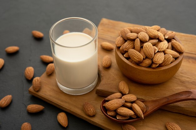 Almond milk with almond in a wooden spoon and bowl on a wooden