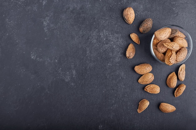 Almond shells in a glass cup and on the black table, top view. 