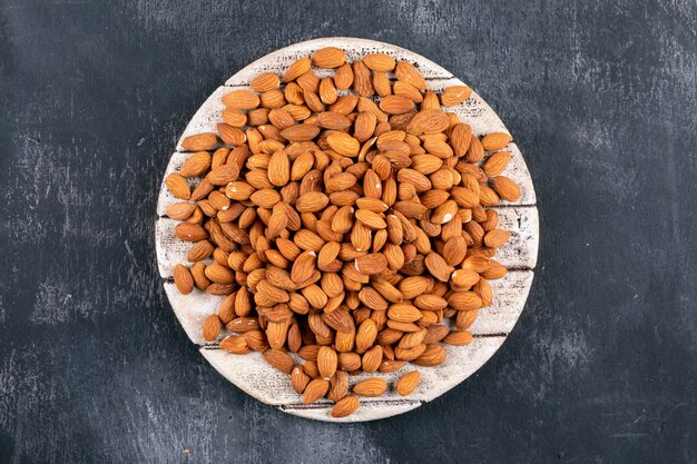 Almond in a wooden board top view on a black stone table