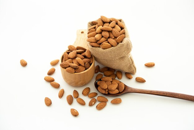 Almond in a wooden spoon and bowl. Sack with almond on white background.