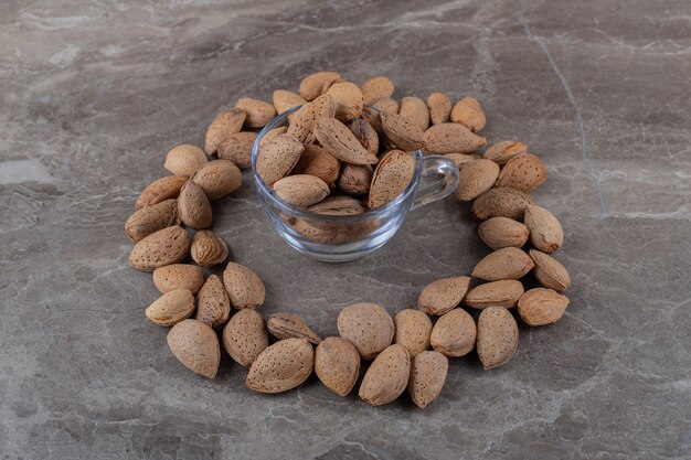 Almonds around a bowl of almonds on the marble surface