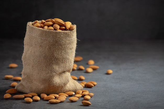 Almonds in bag from sackingl on dark background