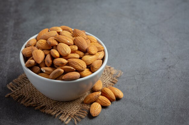 Almonds in bowl on dark background