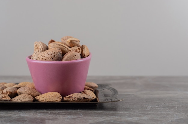 Almonds in a bowl on tray on the marble surface