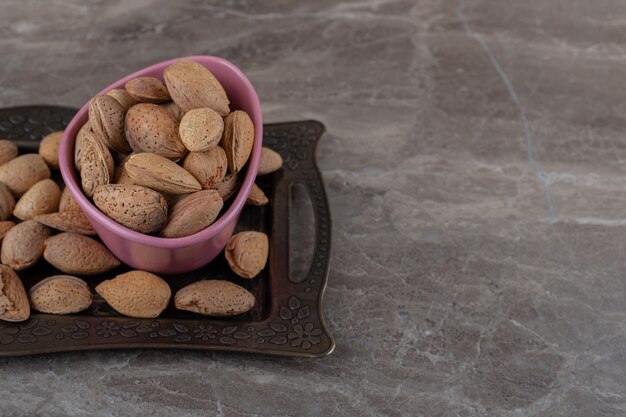 Almonds in a bowl on tray on the marble surface