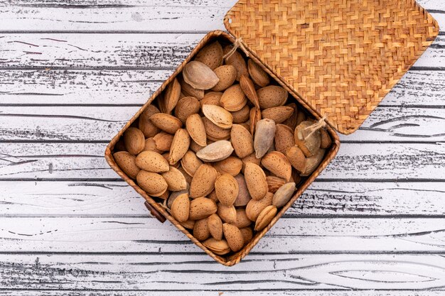 Free photo almonds in box top view on white wooden surface